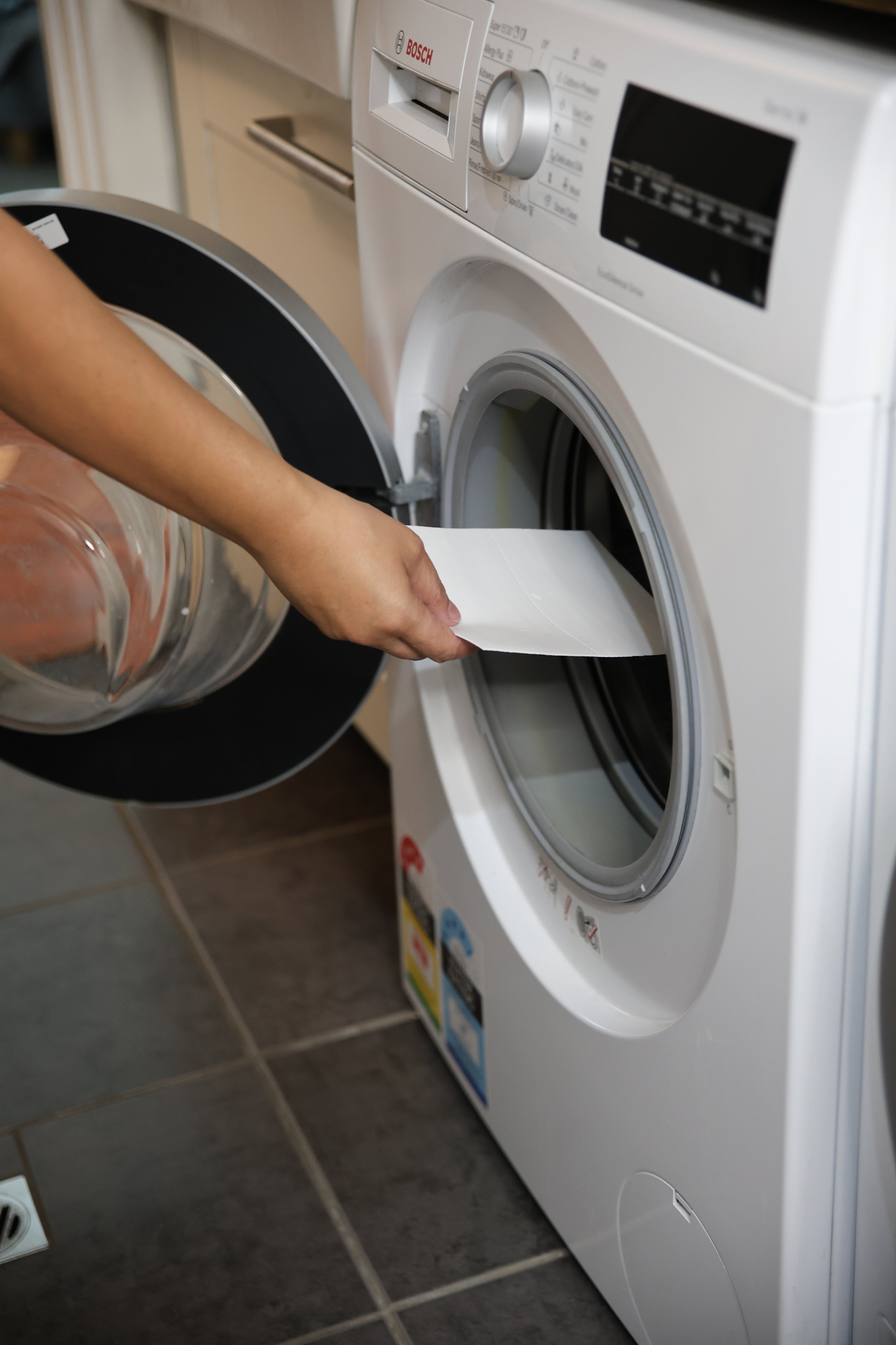 Placing a fragrance free laundry detergent sheet into a washing machine